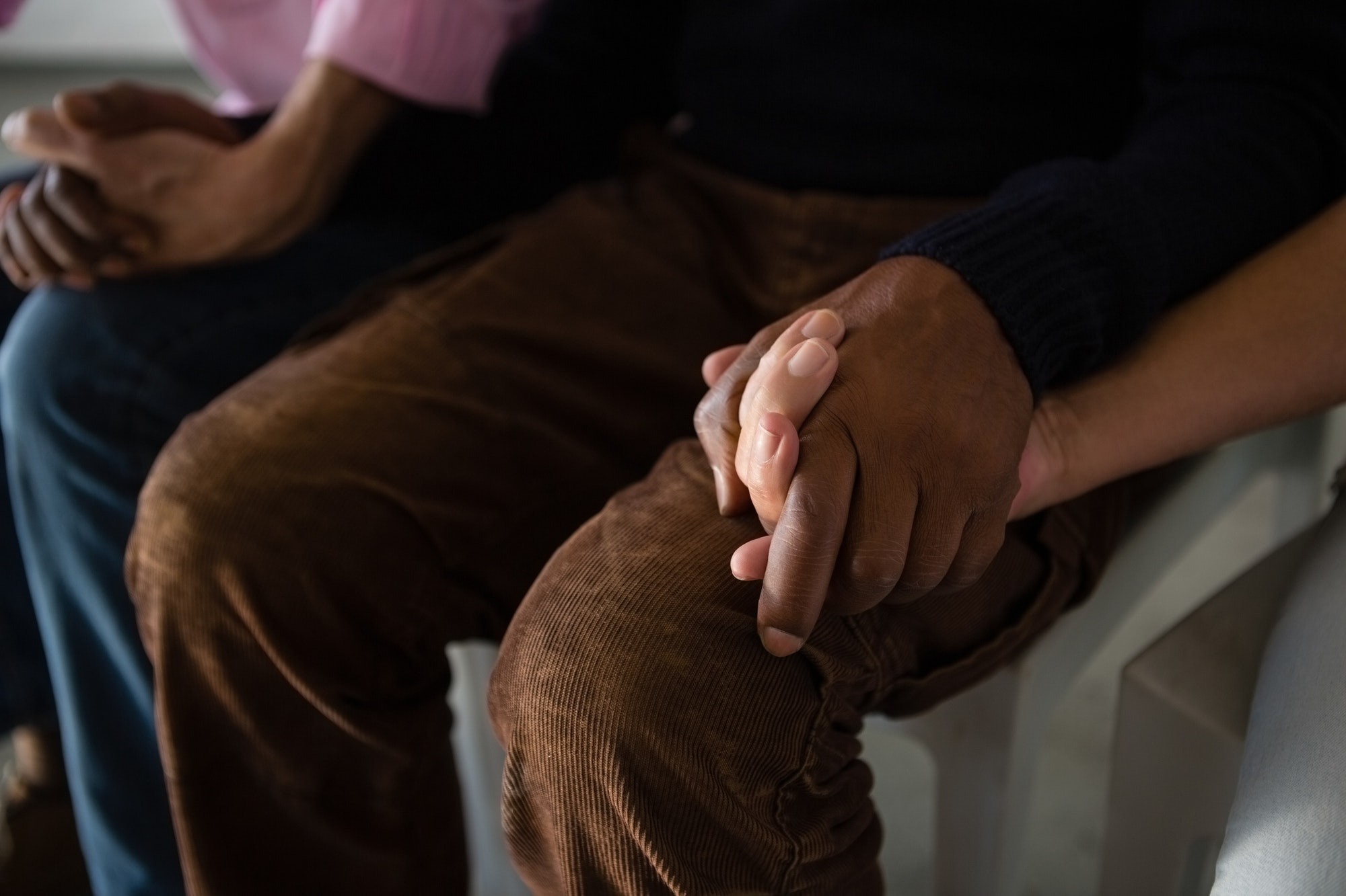 High angle view of senior friends holding hands while sitting on chair