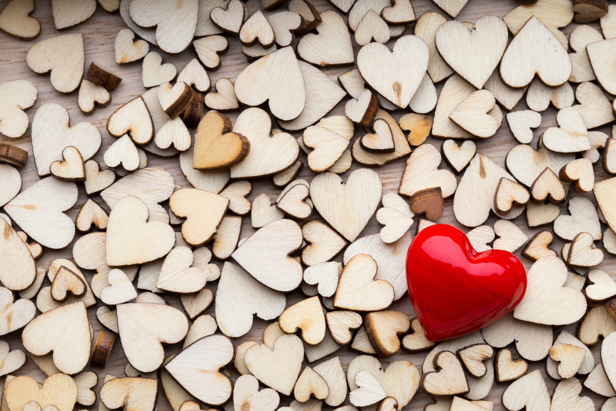 Wooden hearts, one red heart on the heart background.