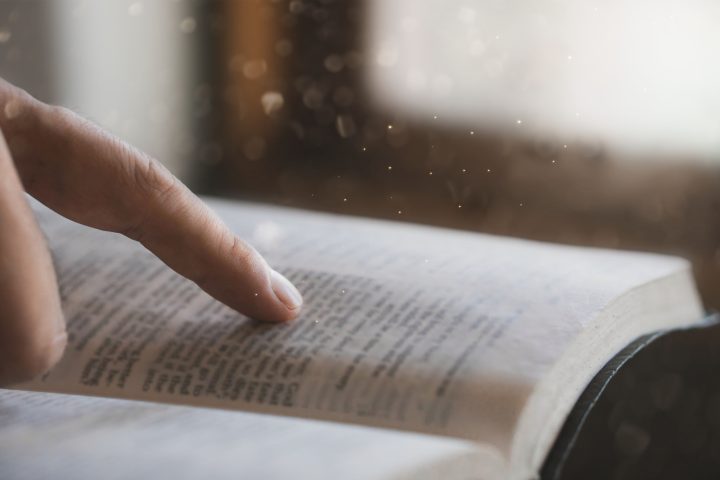 A young man is reading the holy scriptures pointing to a Bible topic. bible book Bible reading